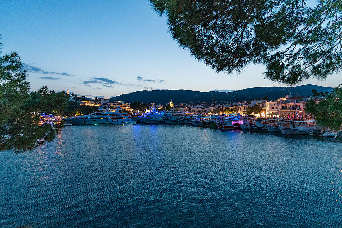 Nächtlicher Blick auf den beleuchteten Hafen und die Boote von Skiathos, Griechenland