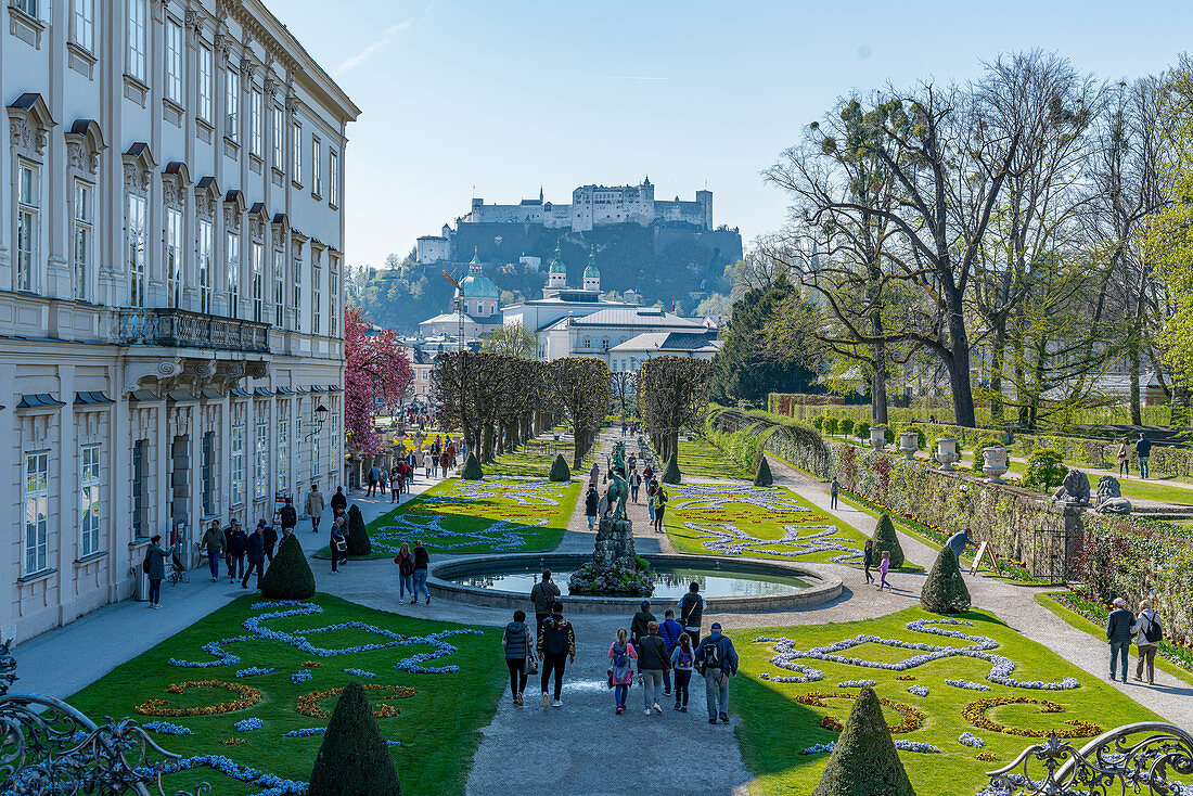 Blick auf die Touristen im Mirabellgarten und auf die Burg Hohensalzburg in Salzburg, Österreich