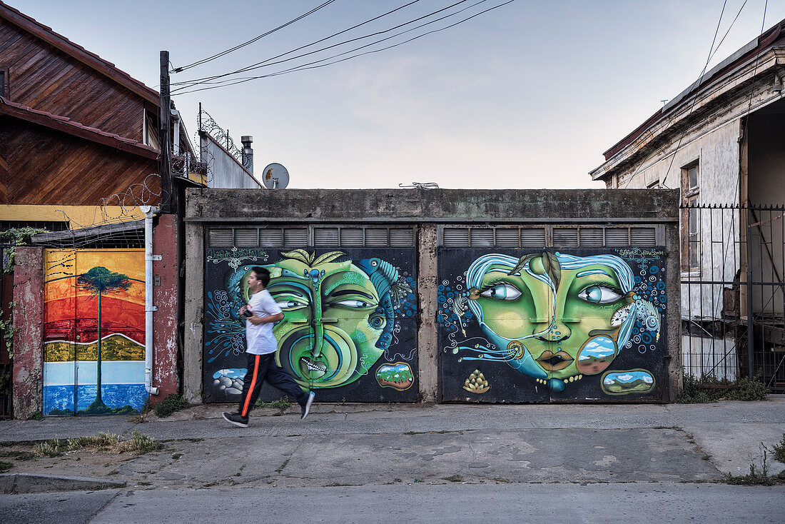 People jog on sidewalk, street art in the streets of Valparaiso, Chile, South America