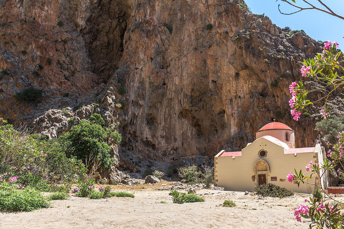 Blühende Sträucher und Kapelle in der Agiofaraggo Schlucht bei Mátala, Süden Kreta, Griechenland