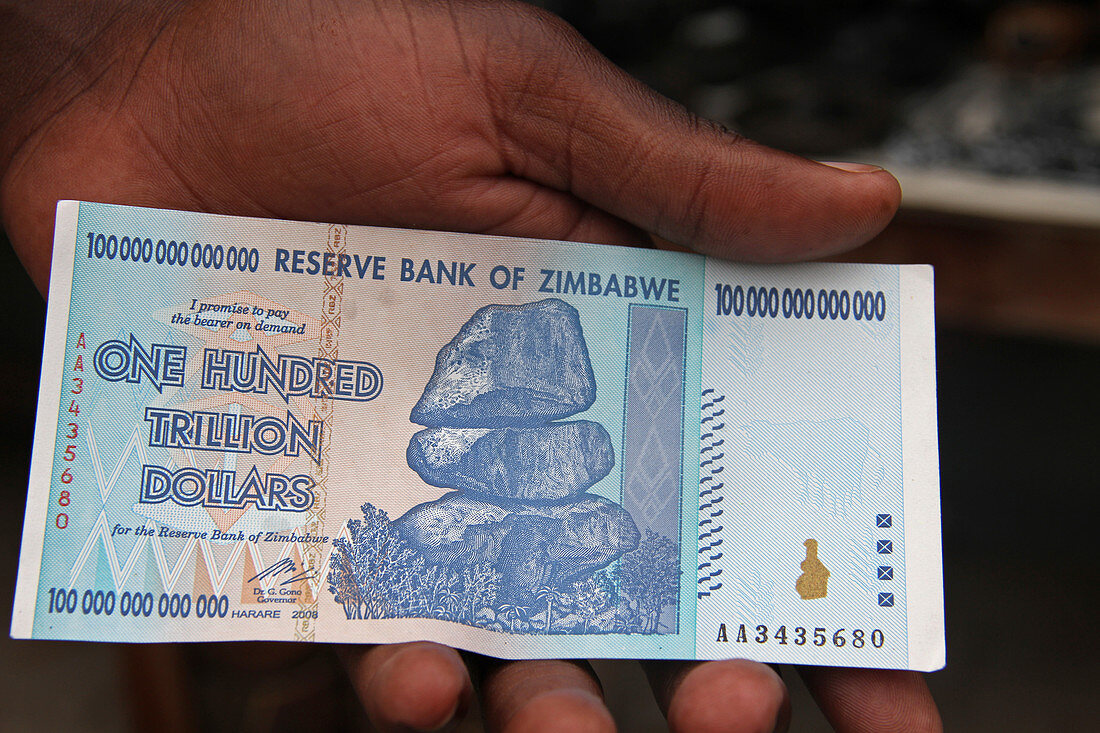 Die Hand eines afrikanischen Mannes mit einem Hundert-Trillionen-Dollar-Schein, Simbabwe.