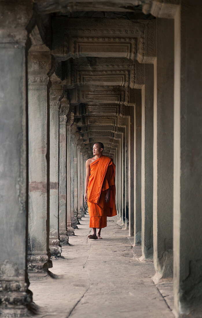 Siem Reap, Cambodia - January 19, 2011: A monk is wearing a orange robe and walking in the Angkor Wat complex.