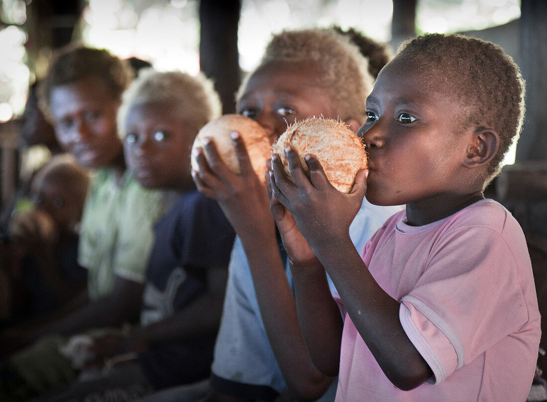 Papua-Neuguinea - 12. November 2010: Zwei Jungen trinken Wasser aus einer Kokosnuss