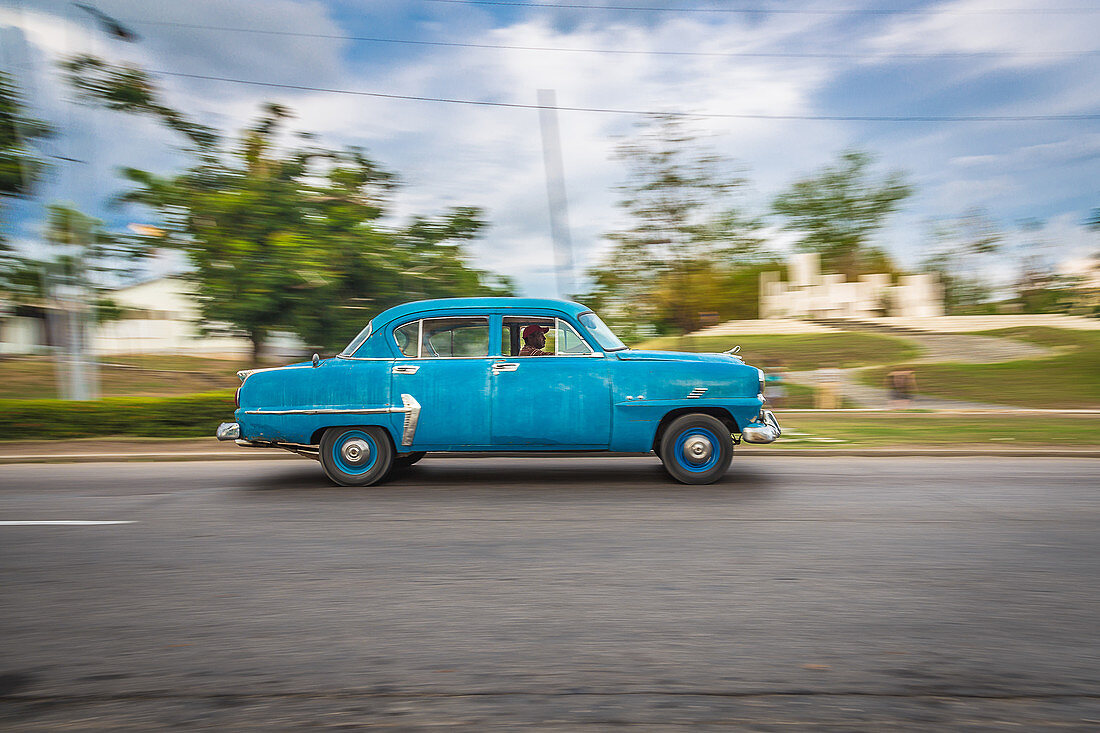 Blauer Oldtimer fährt durch die Straßen von Santiago de Cuba, Kuba