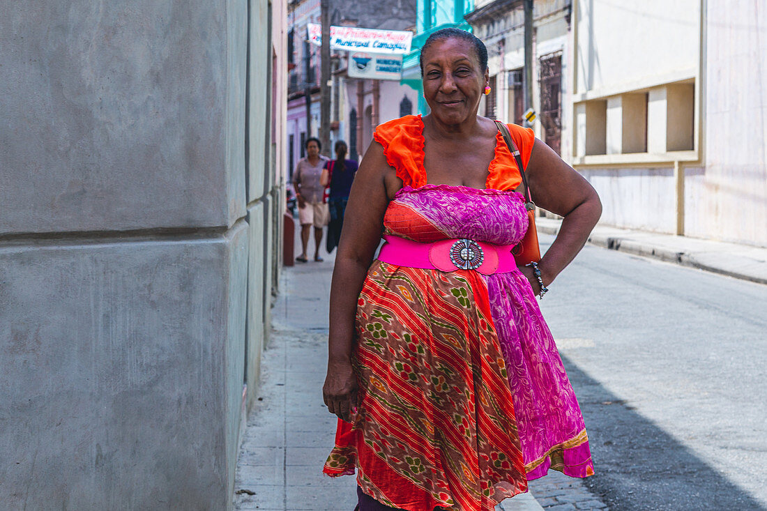 Cuban woman in colorful dress stands on the street, Camagüey, Cuba