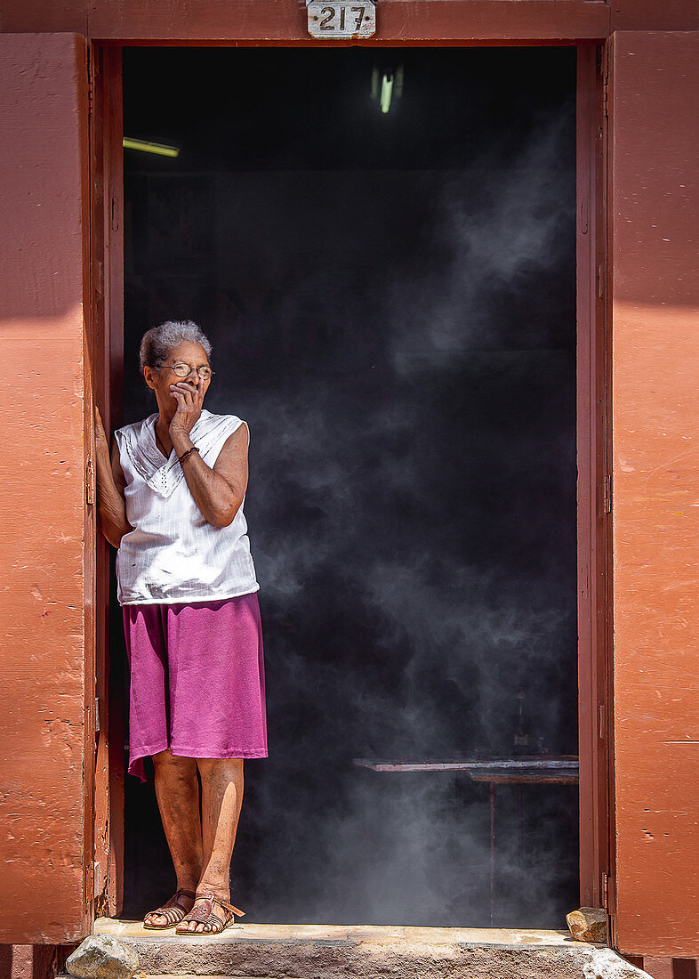 Frau hustet weil es in der Küche raucht, Trinidad, Kuba