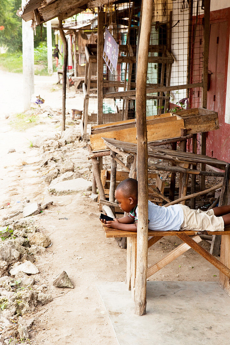 Kenyan child with smartphone, ruined city, Gede, Malindi, Kenya