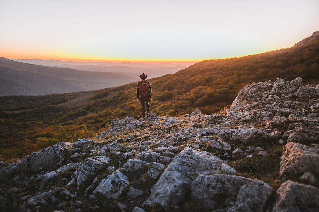 Mann steht auf Felsen in den Bergen bei Sonnenuntergang