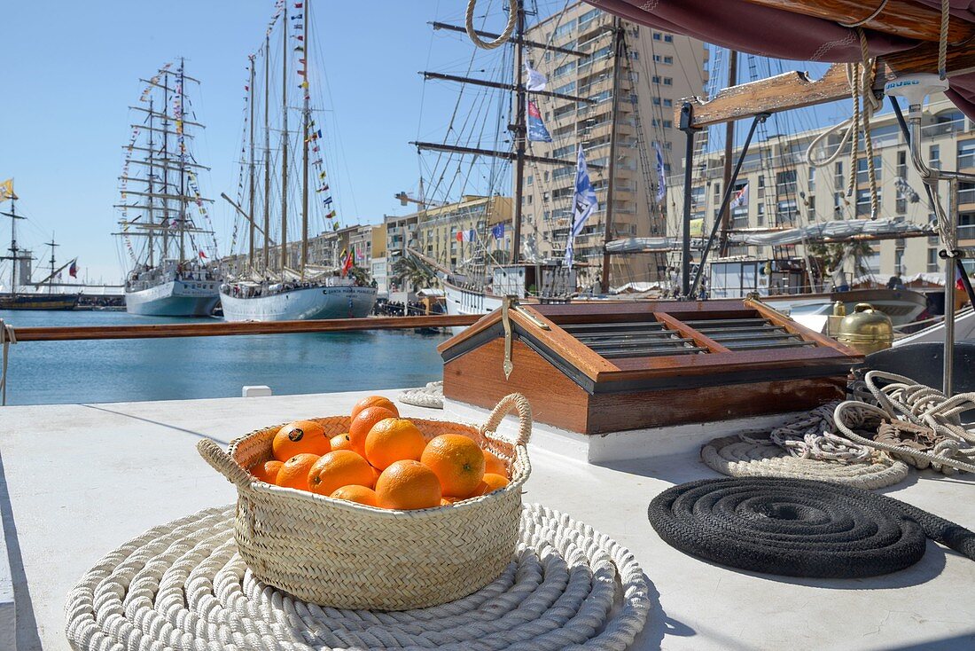 Frankreich, Hérault, Sète, Festival Escale à Sète, Korb mit Orangen auf dem Deck eines Segelbootes, Hafen und Boote im Hintergrund