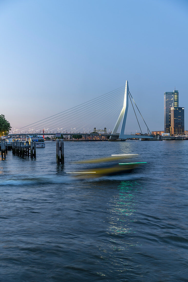 Blick während der Blauen Stunde über die Neue Maas auf die Erasmusbrücke mit einem Wassertaxi im Vordergrund, Rotterdam, Niederlande