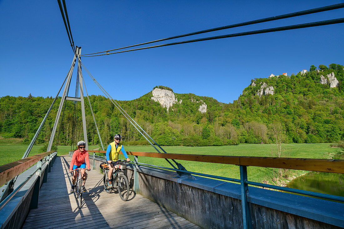 Mann und Frau fahren auf dem Rad über Brücke im Oberen Donautal, nahe Beuron, Oberes Donautal, Donau-Radweg, Baden-Württemberg, Deutschland