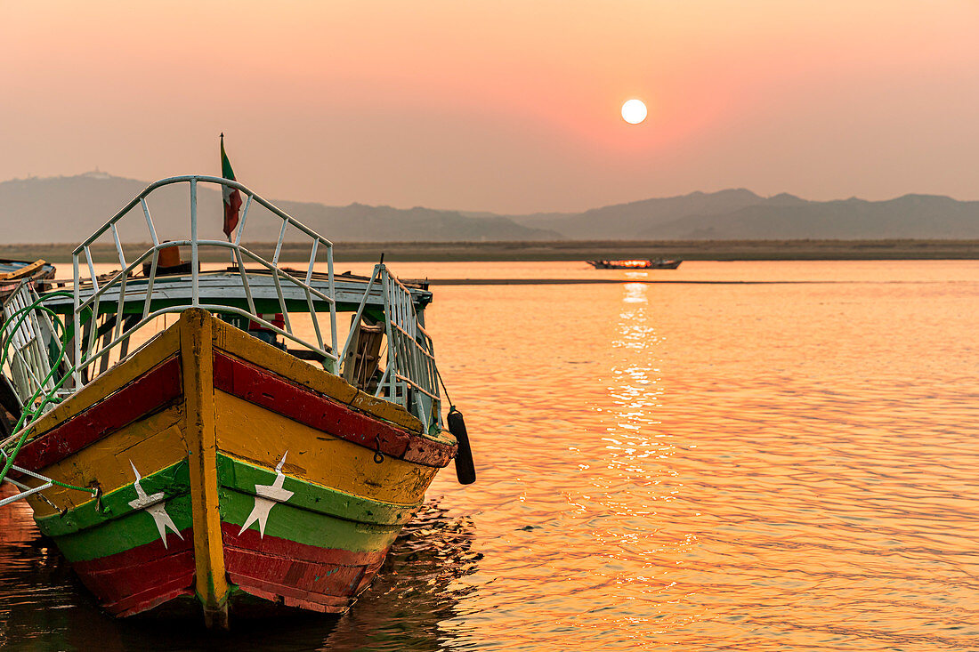 Boot mit Farben der Flagge von Myanmar am Ufer des Irrawaddy Fluss zum Sonnenuntergang, Bagan, Myanmar