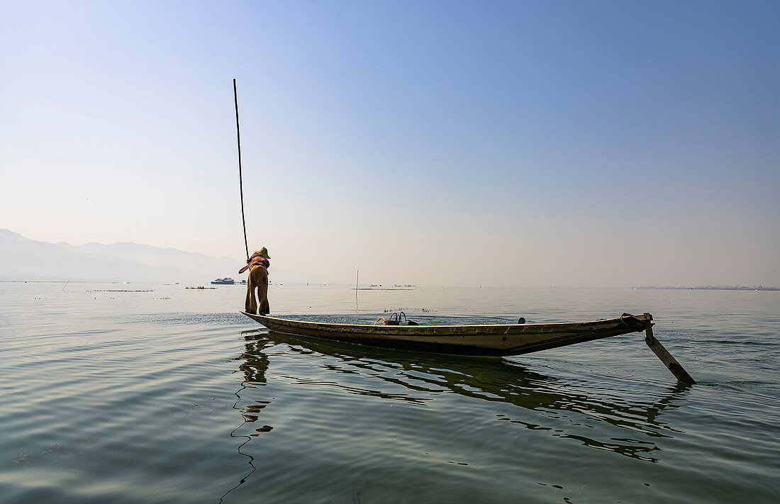 Fischer auf kleinem Boot mit langem Stock zum Fischfang auf dem Inle See, Heho, Myanmar