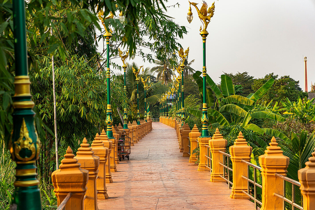 Weg mit orangenen Steinpfeilern durch die Natur im Abendlicht auf Koh Kret, Bangkok, Thailand