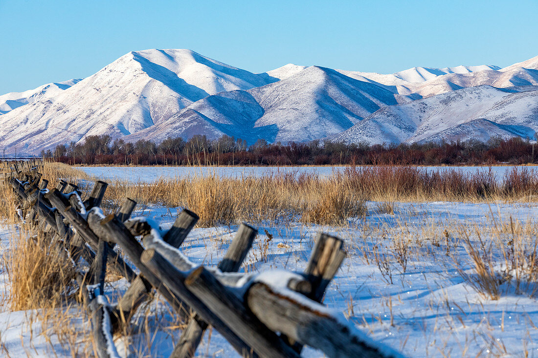 Fence in snow by mountains