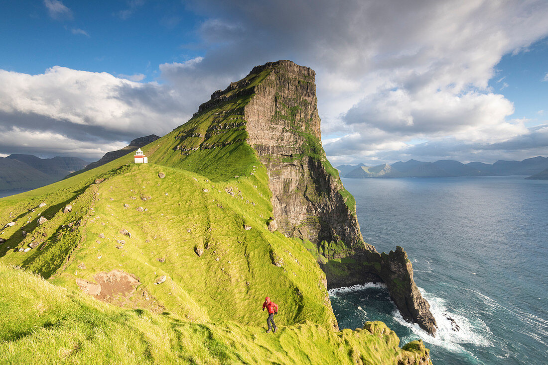 Wanderer läuft auf steilen Klippen am Kallur Leuchtturm, Insel Kalsoy, Färöer-Inseln, Dänemark