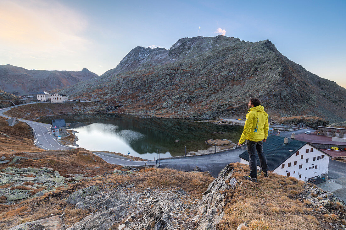 Hiker admires at sunrise the lake at Gran San Bernardo Pass, Aosta Valley, Italy, Europe