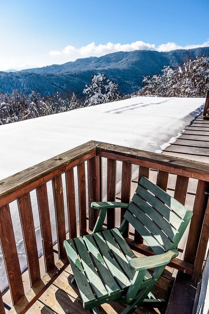 Stuhl auf Balkon vor verschneiter Landschaft, Himmelberg, Kärnten, Österreich