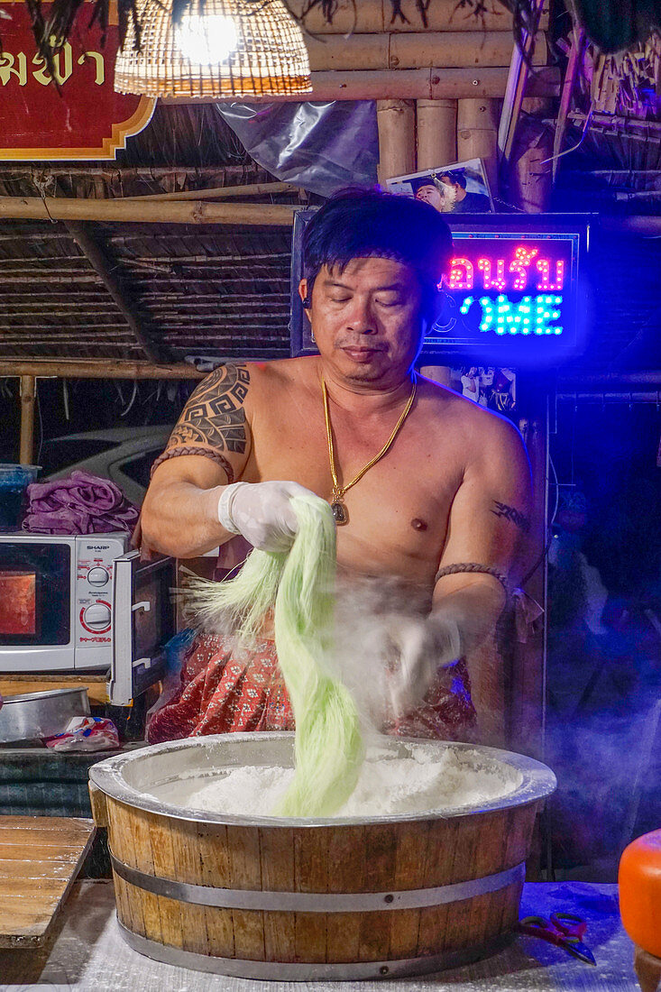 Thai in traditioneller Kleidung formt Nudeln auf dem Nachtmarkt Kungsri in Ayutthaya, Thailand