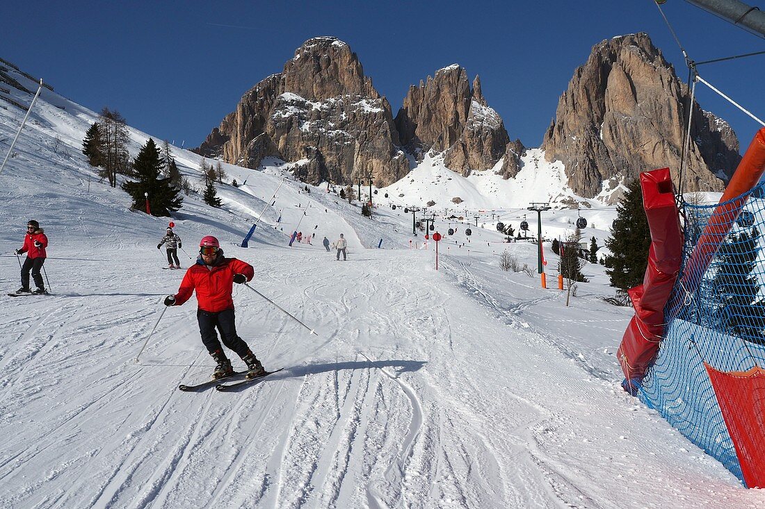 Ski under the Langkofel over Campitello, skier, ski slope, rocks, Dolomites, Trentino in winter, Italy
