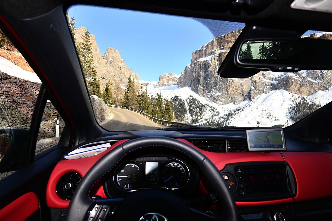From the car on the pass road of the Sella Joch, driver, steering wheel, rocks, windshield, view, scenery, Dolomites, Trentino in winter, Italy
