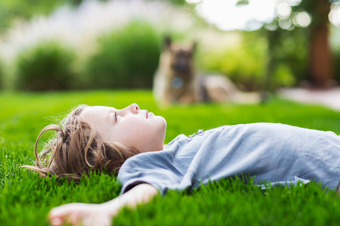 5 year old boy lying down on lush green lawn looking up