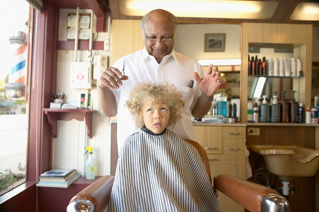 Friseur prüft lockige Haare von einem Jungen