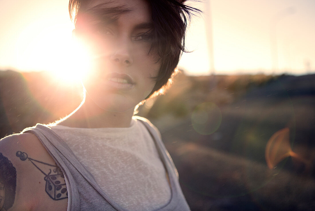 A young woman standing outdoors at sunset.