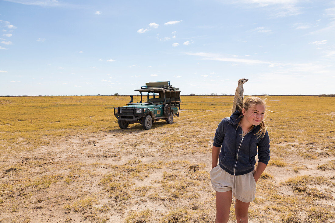 Zwölfjähriges Mädchen mit Erdmännchen auf der Schulter, Kalahari-Wüste