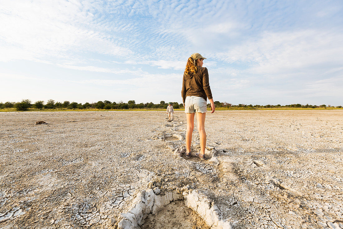 13 year old girl leaping into elephant footprints, Nxai Pan, Botswana