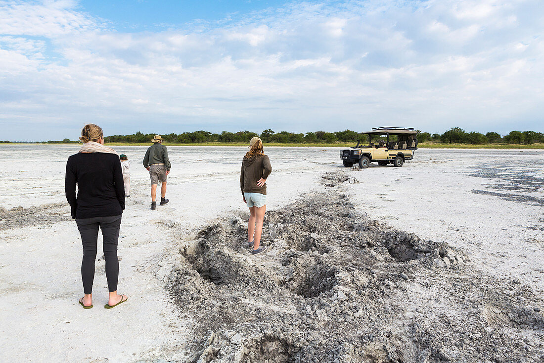 family looking at elephant footprints, Nxai Pan, Botswana