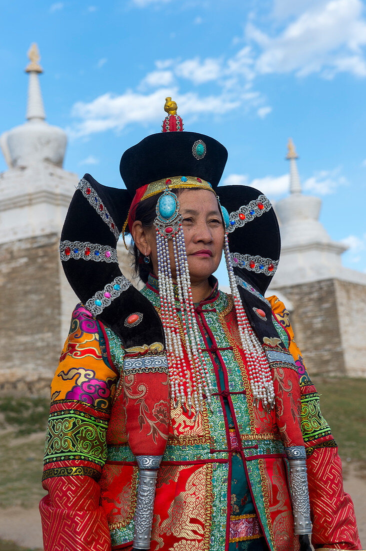 Eine mongolische Frau in historischer Tracht vor der Mauer mit Stupas, die das Kloster Erdene Dsuu umgeben, Kharakhorum (Karakorum), UNESCO-Weltkulturerbe, Mongolei