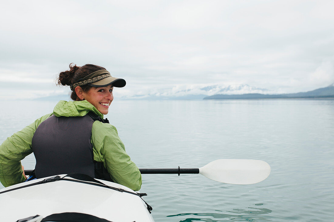 Glückliche Frau unterwegs mit Kajak, unberührte Gewässer von Muir Inlet in Glacier-Bay-Nationalpark, Alaska