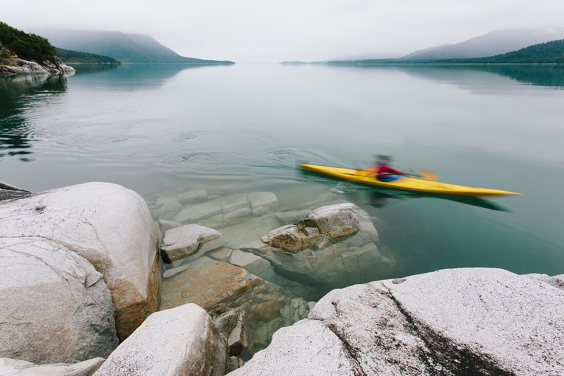 Frau unterwegs mit Kajak, unberührtes Wasser von Muir Inlet, bewölkter Himmel in der Ferne, Glacier-Bay-Nationalpark, Alaska