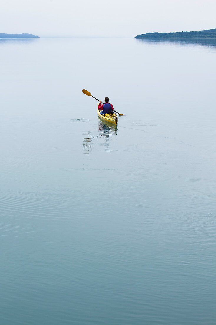 Frau unterwegs mit Kajak, unberührtes Wasser von Muir Inlet, bewölkter Himmel in der Ferne, Glacier-Bay-Nationalpark, Alaska