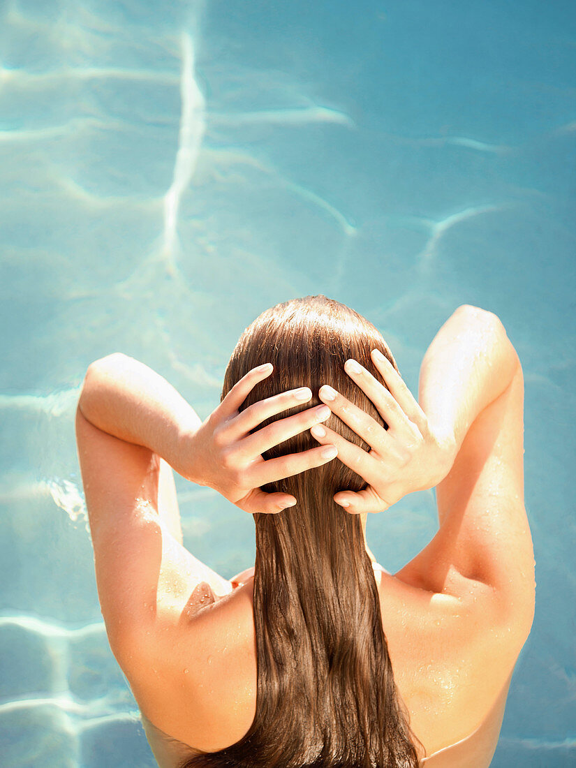 Rückansicht einer Frau im Wasser mit Händen auf dem Kopf in einem Luxusresort in Kalifornien