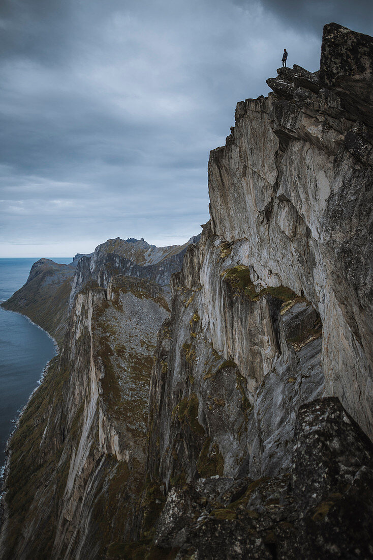 Norwegen, Senja, Mann steht am Rande einer steilen Klippe auf dem Berg Segla