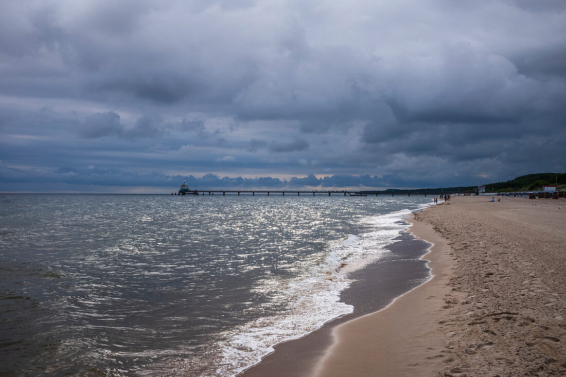 Baltic sea beach pier in Zinnowitz with cloudy skies and waves, Usedom, Mecklenburg-Western Pomerania, Germany