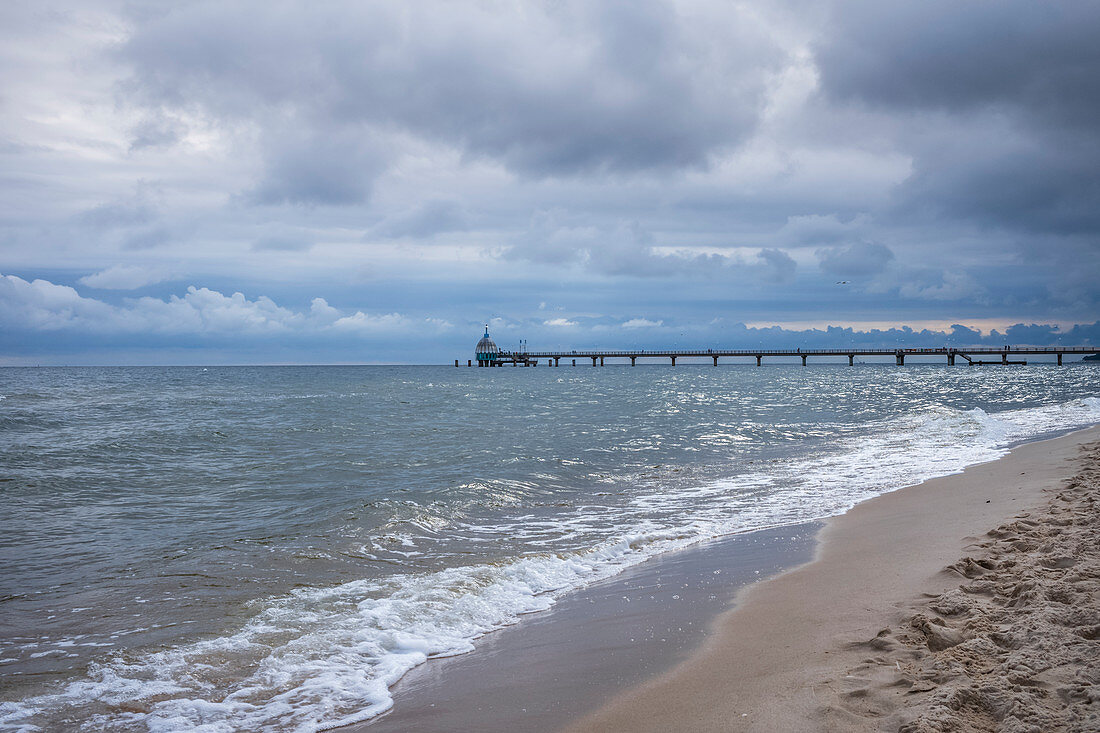 Baltic Sea beach with a view of the pier in Zinnowitz with cloudy skies and waves, Usedom, Mecklenburg-Western Pomerania, Germany