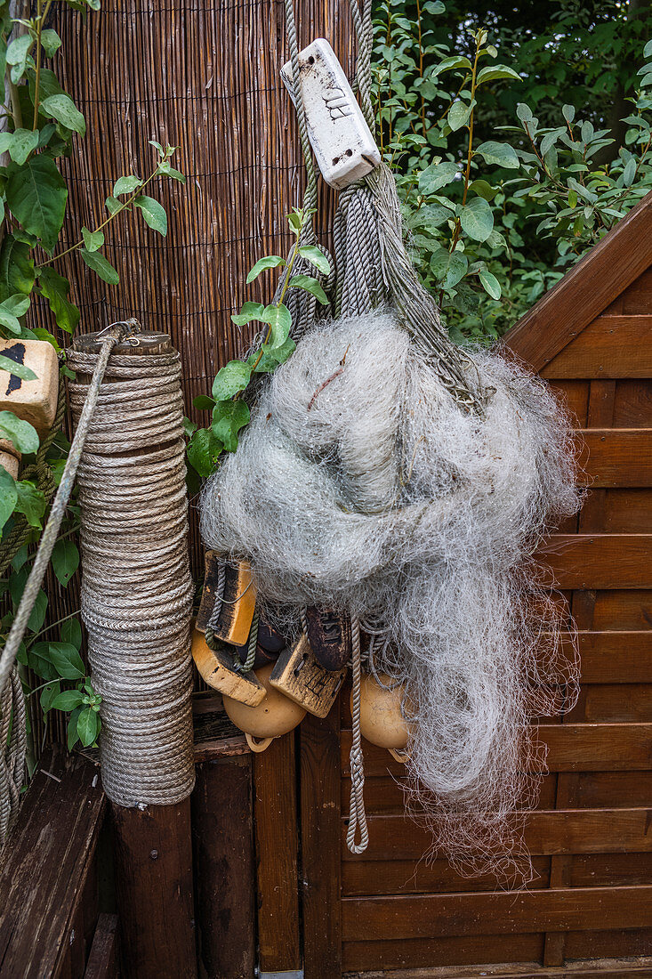 Old fishing net with buoys hangs on the fence, Usedom, Mecklenburg-Western Pomerania, Germany