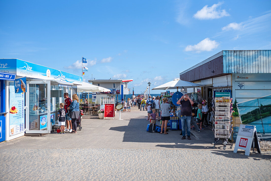 Zugang zur Seebrücke in Zinnowitz bei blauem Sommerhimmel mit Menschen und Shops, Usedom, Mecklenburg-Vorpommern, Deutschland