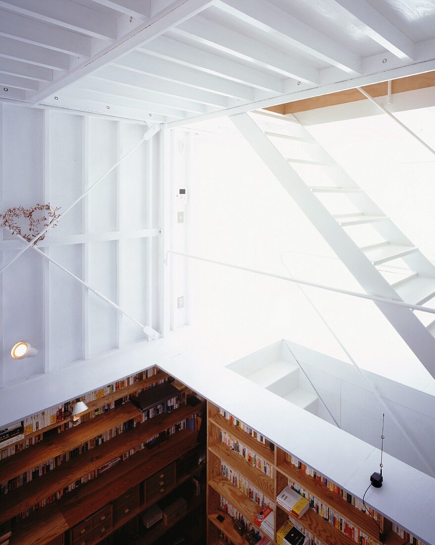 A gallery with a white staircase and a view into an open study