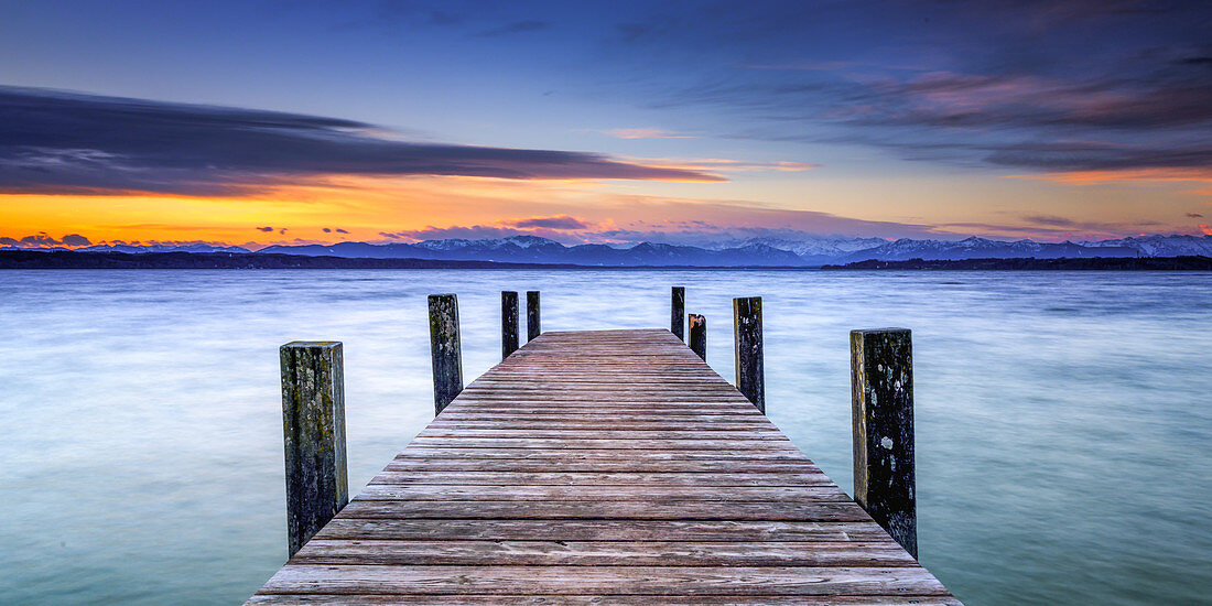 Jetty in sunrise on Lake Starnberg with mountain view, Bavaria, Germany