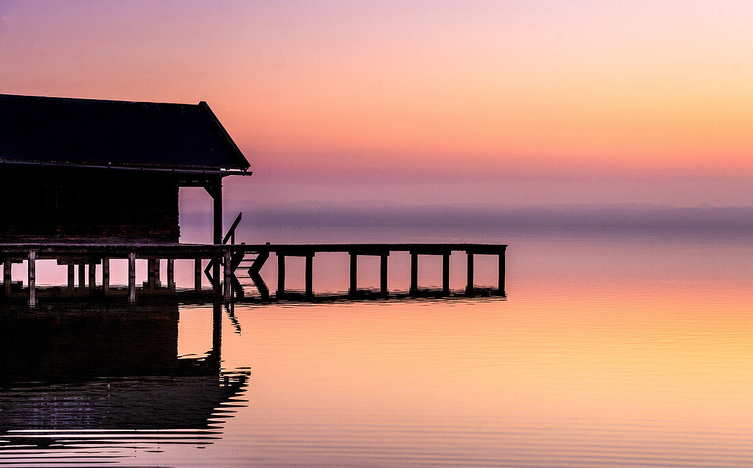 Boathouse silhouette at sunrise on Lake Starnberg, Bavaria, Germany