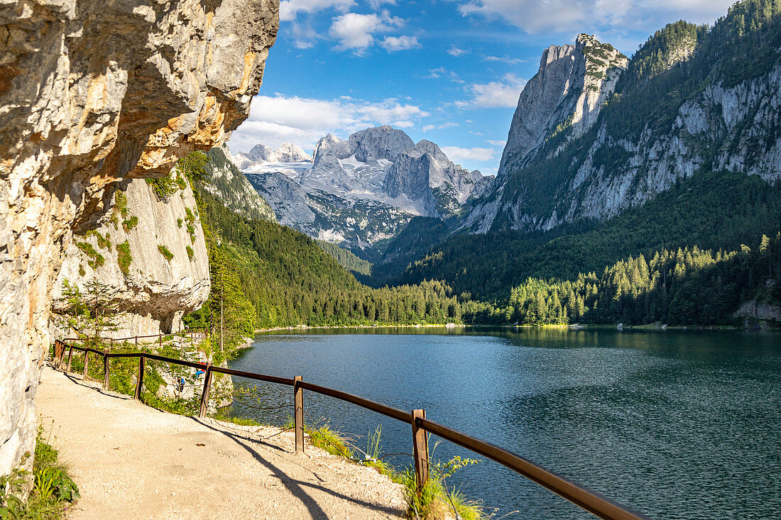 Large Gosau lake with climbing walls and a path in the foreground. View of the Dachstein massif, Salzkammergut, Upper Austria.