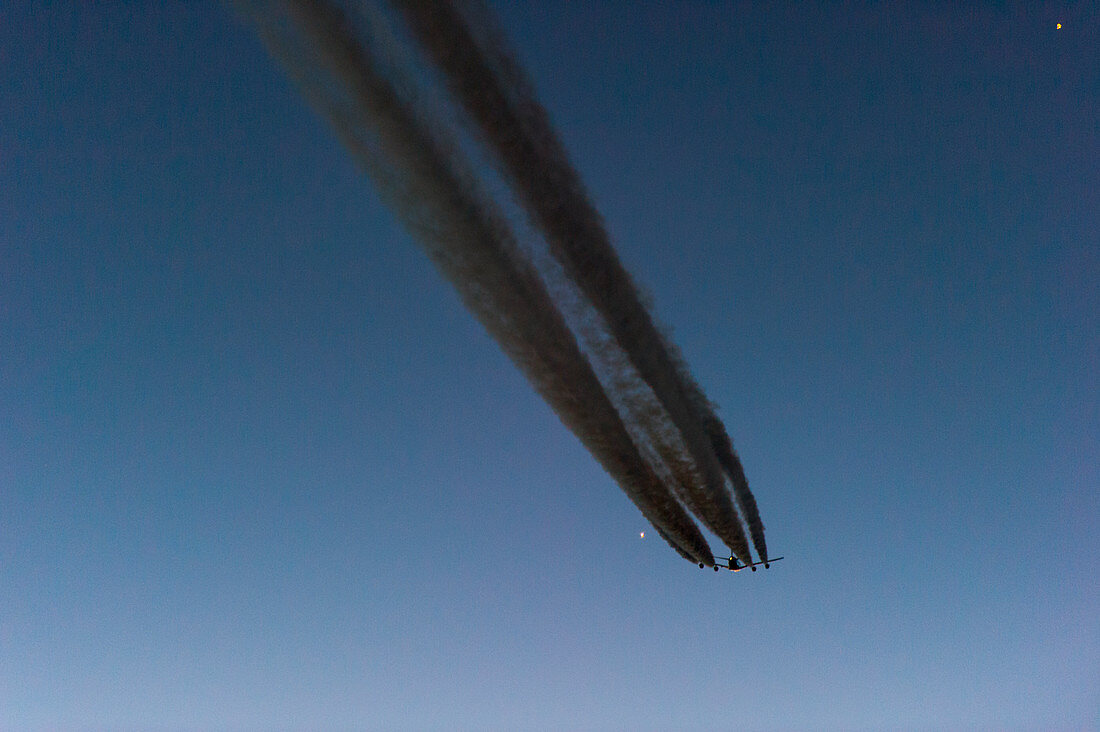 Flugzeug mit Kondensstreifen in der Morgendämmerung