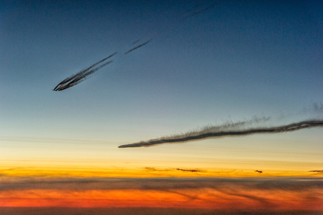Airplanes with contrails just before sunrise