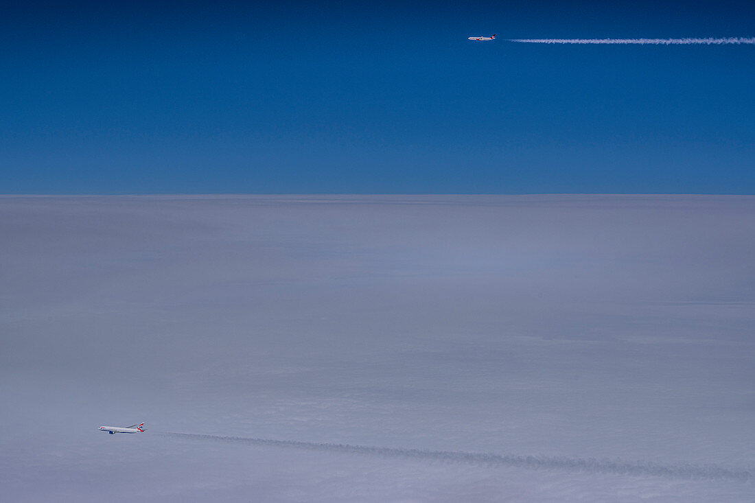 Flugzeuge mit Kondensstreifen über geschlossener Wolkendecke