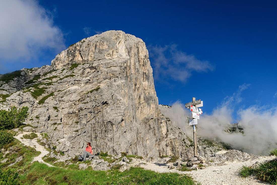 Frau beim Wandern sitzt vor Gipfel des Pizzocco, Belluneser Dolomiten, Nationalpark Belluneser Dolomiten, UNESCO Welterbe Dolomiten, Venezien, Venetien, Italien