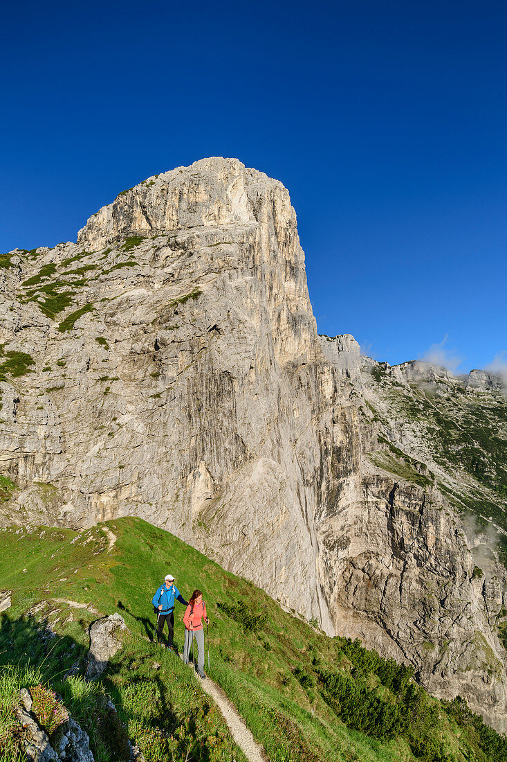 Man and woman hiking in front of the summit of Pizzocco, Belluno Dolomites, Belluno Dolomites National Park, UNESCO World Heritage Dolomites, Veneto, Veneto, Italy